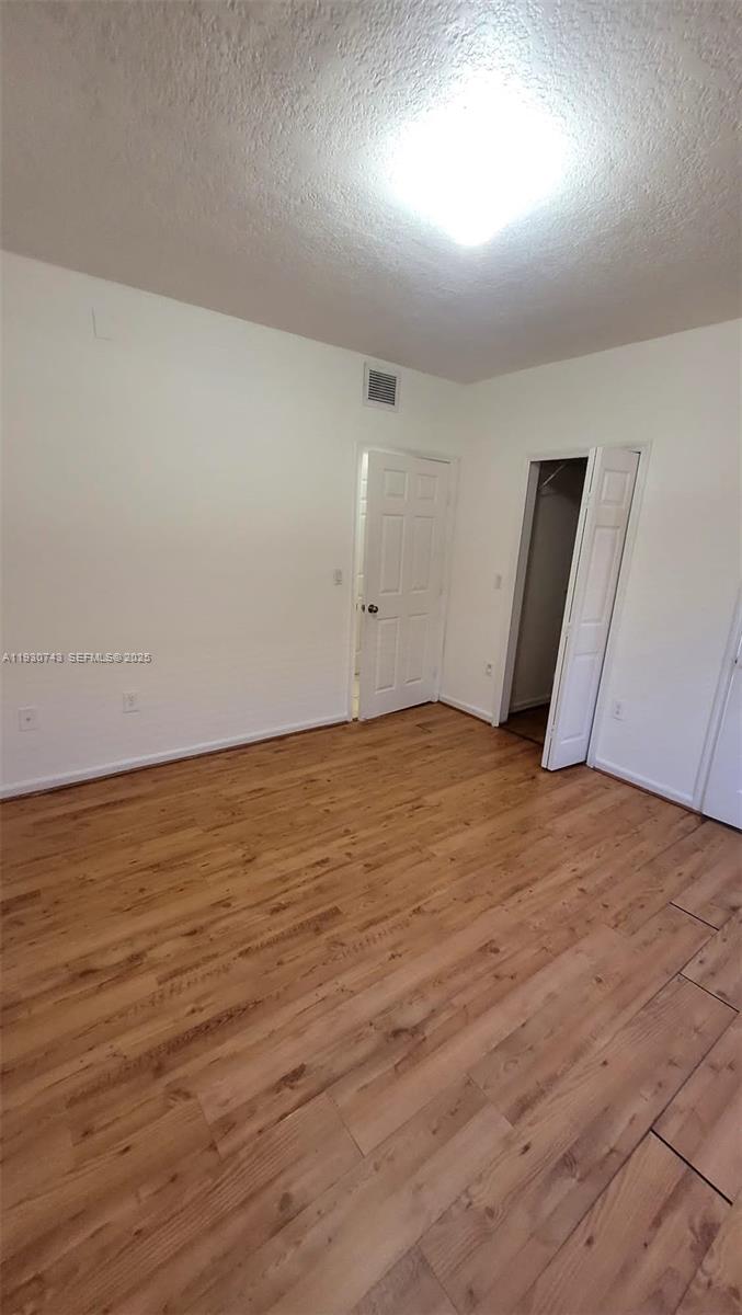 7241 Northwest 174th Terrace, Unit 103 Hialeah, FL 33015 - Photo 6 of 19 an empty room with wooden floor and windows