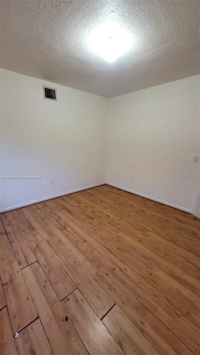 7241 Northwest 174th Terrace, Unit 103 Hialeah, FL 33015 - Photo 8 of 19 an empty room with wooden floor and windows