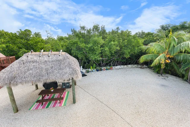 a view of a patio with a table and chairs under an umbrella next to a yard