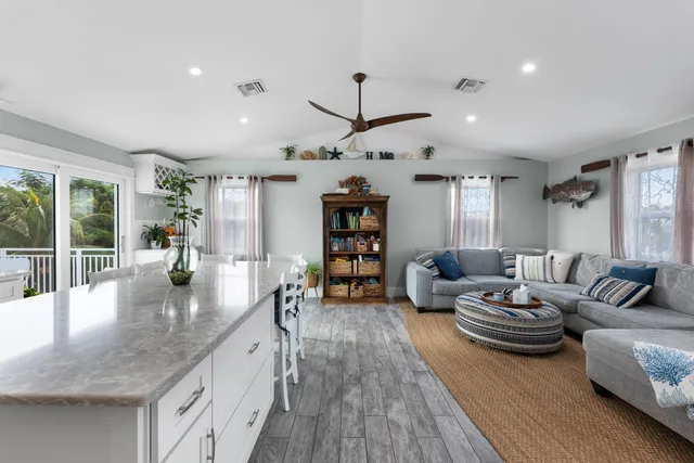 a living room with furniture kitchen view and a large window