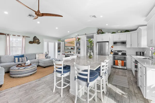 a kitchen with stainless steel appliances kitchen island granite countertop a dining table chairs and view of living room