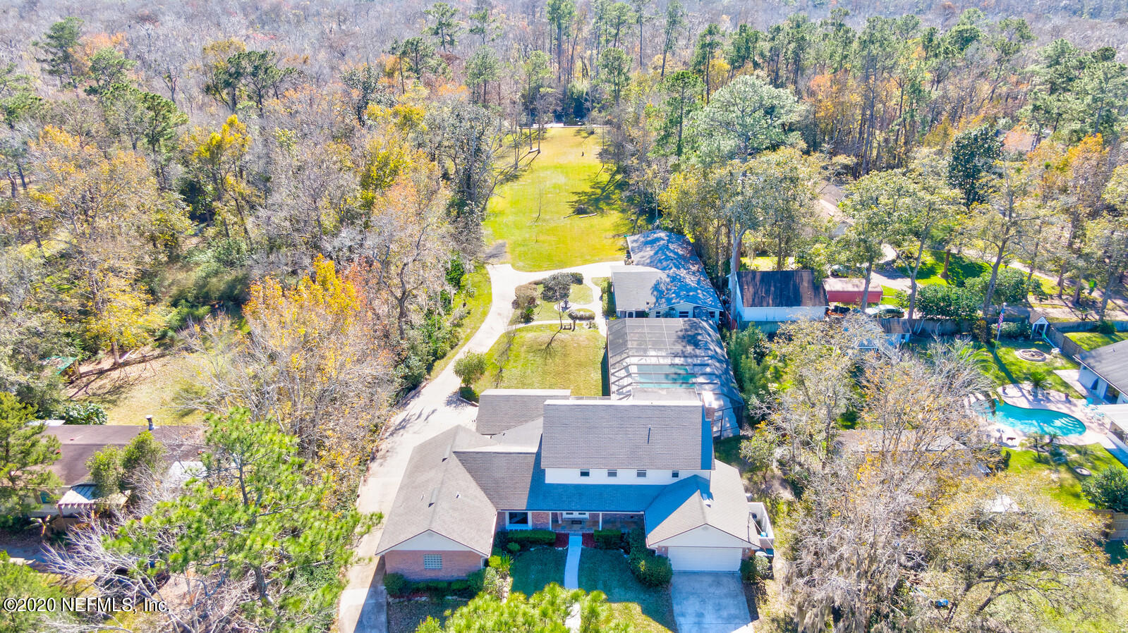 aerial view of a house with swimming pool and large trees