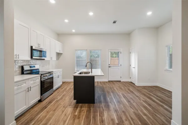 a kitchen with granite countertop a stove top oven a sink dishwasher and a refrigerator with wooden floor