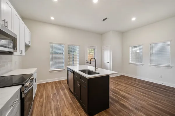 a kitchen that has a sink a stove and wooden floor