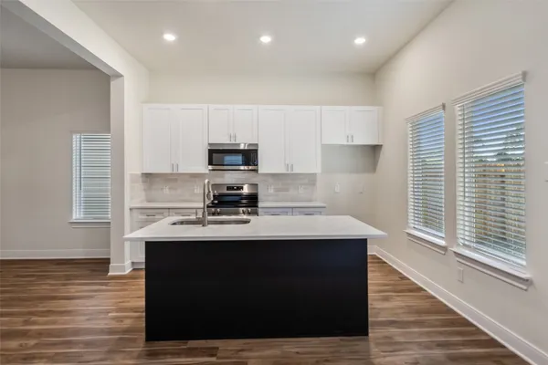 a kitchen with kitchen island a sink dishwasher a stove and a refrigerator with wooden floor