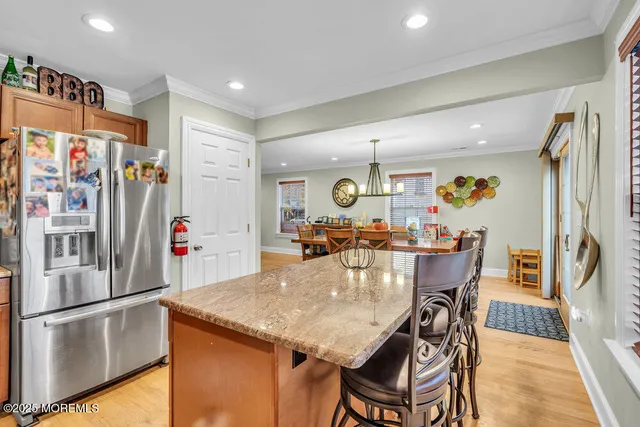 a kitchen with stainless steel appliances granite countertop a refrigerator a stove a sink a dining table and chairs with wooden floor