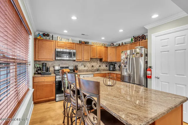 a kitchen with stainless steel appliances granite countertop a table chairs and a refrigerator