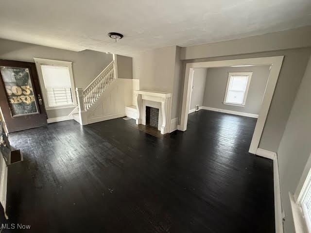 4372 Turney Road Cleveland, OH 44105 - Photo 7 of 16 Unfurnished living room with dark wood-style flooring, stairs, and a fireplace