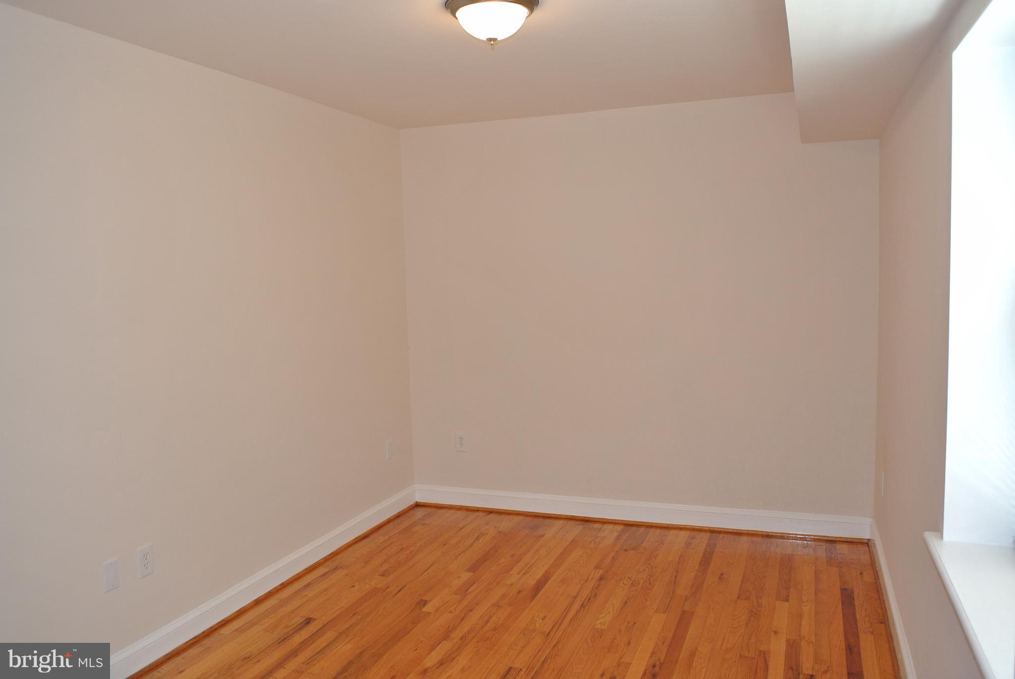 3216 28th Street Southeast, Unit 2 Washington, DC 20020 - Photo 9 of 17 a view of an empty room with wooden floor and a window