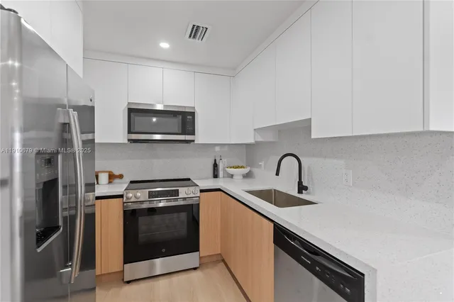 a kitchen with stainless steel appliances granite countertop a sink a stove a refrigerator and cabinets