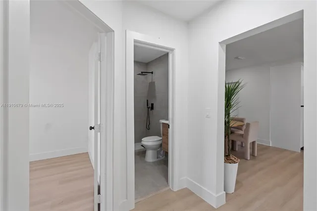 a view of a hallway with wooden floor and a bathroom