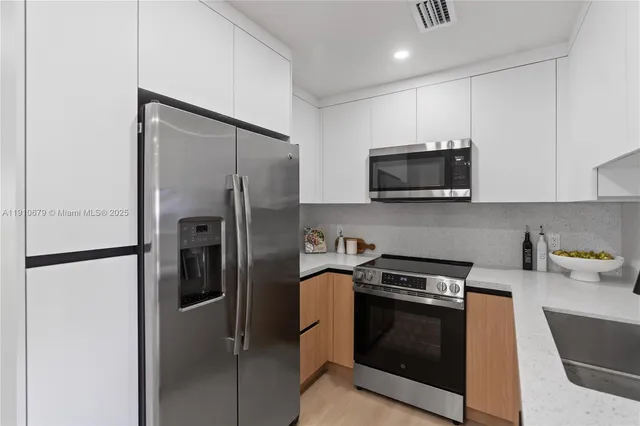 a kitchen with stainless steel appliances a refrigerator a stove a microwave a sink and cabinets