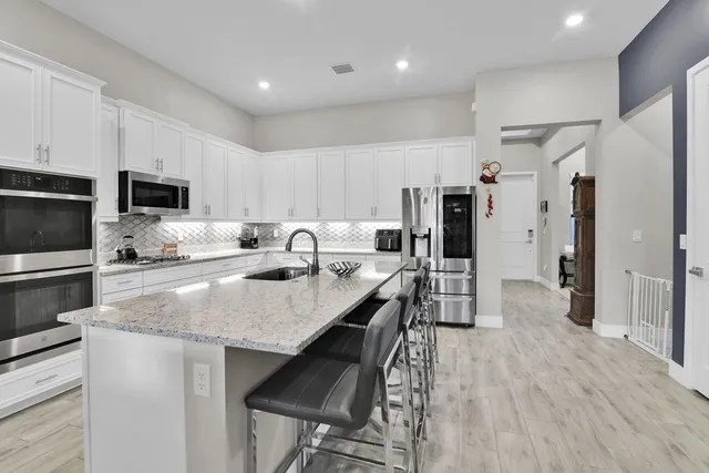 a kitchen with stainless steel appliances kitchen island granite countertop a table chairs sink and cabinets