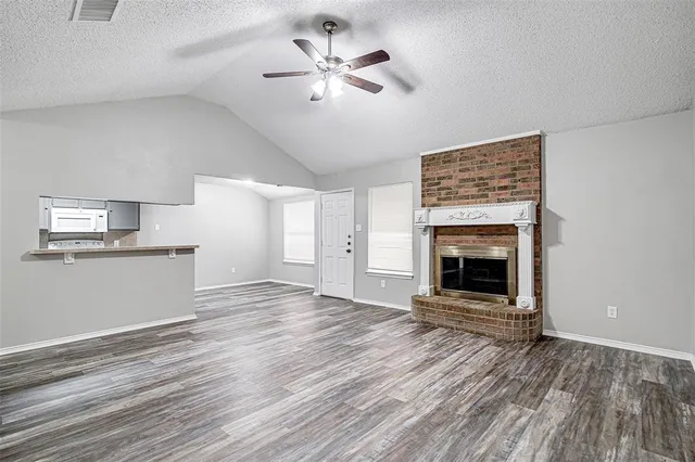 a view of kitchen and empty room with wooden floor