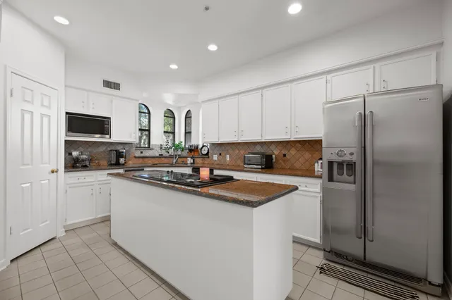 a kitchen with stainless steel appliances granite countertop a refrigerator sink and white cabinets