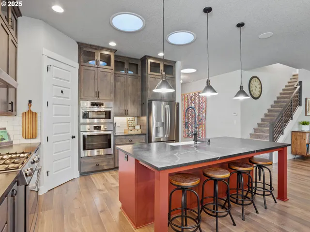 a kitchen with stainless steel appliances kitchen island granite countertop a stove a sink and a wooden cabinets