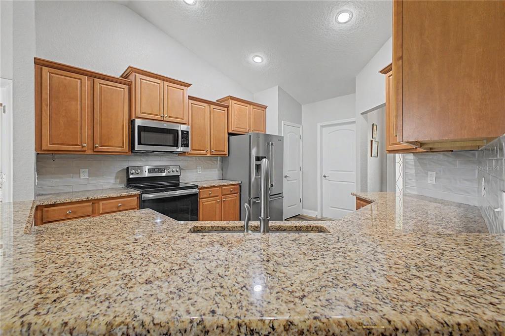 11213 Flock Avenue Weeki Wachee, FL 34613 - Photo 7 of 46 a kitchen with stainless steel appliances granite countertop a refrigerator a stove top oven and a sink