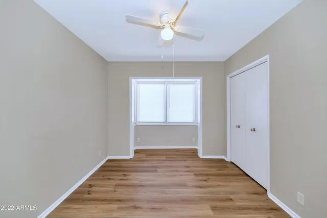 a view of empty room with wooden floor and fan