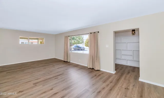 an empty room with wooden floor cabinet and windows