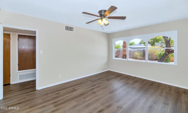 a view of an empty room with wooden floor and a window