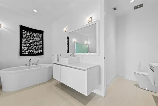 a spacious bathroom with a double vanity sink toilet mirror and bathtub