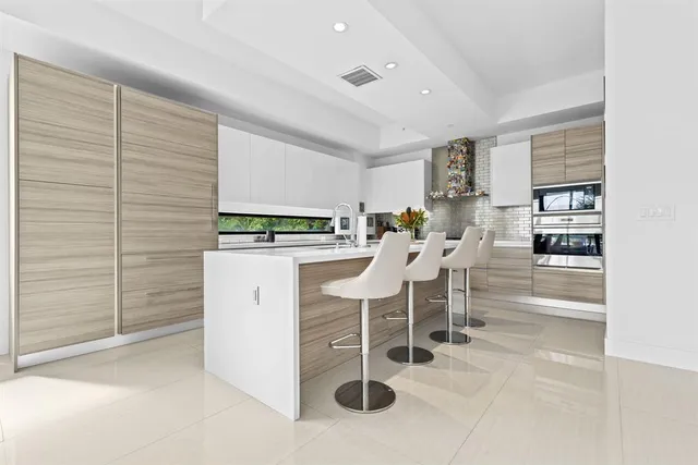 a kitchen with stainless steel appliances kitchen island granite countertop a table chairs and a refrigerator