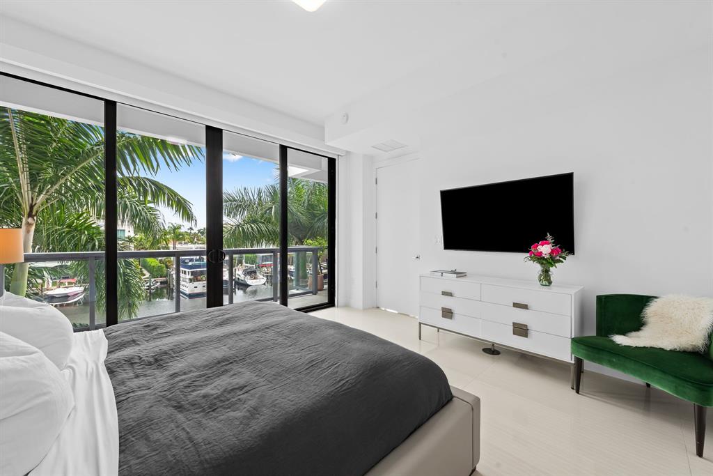 60 Hendricks Isle, Unit 301 Fort Lauderdale, FL 33301 - Photo 10 of 31 a bedroom with a bed and a flat tv screen next to a large window