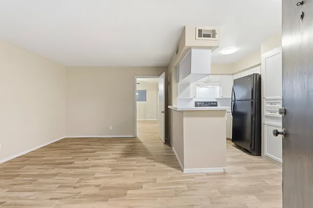 a view of a kitchen with refrigerator and white cabinets