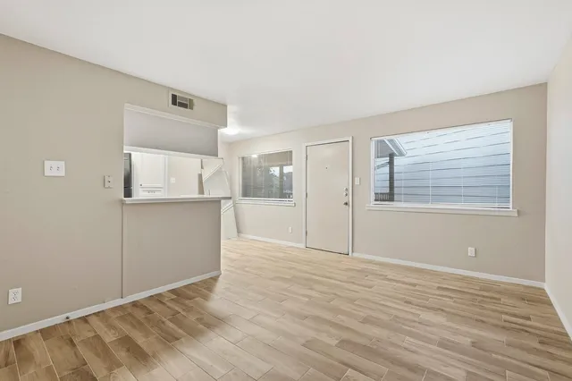 a view of an empty room with wooden floor and a window