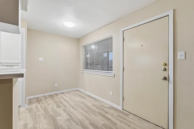 a view of an empty room with window and wooden floor