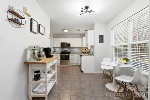a kitchen with stainless steel appliances kitchen island granite countertop a refrigerator a stove a sink dishwasher and a dining table with wooden floor