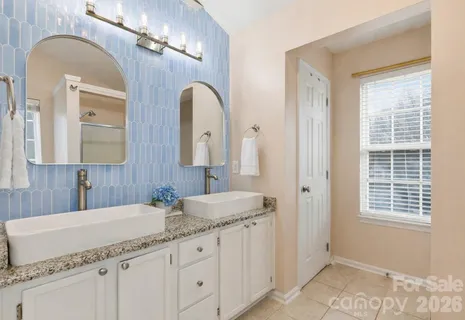 a bathroom with a granite countertop double vanity sink a mirror and