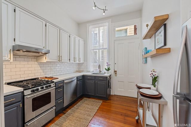 a kitchen with stainless steel appliances a stove a sink and cabinets