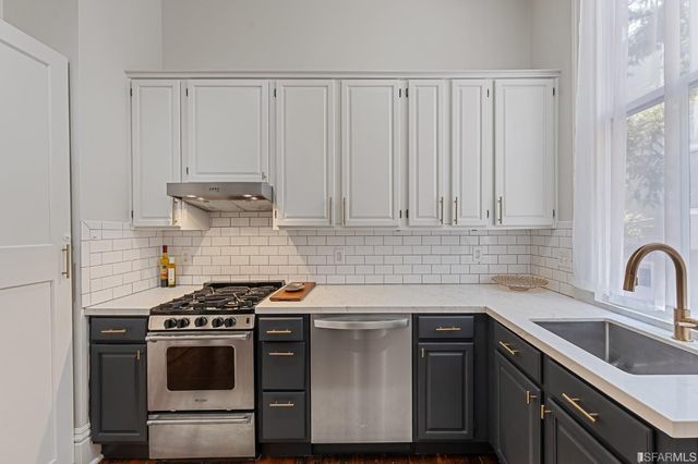 a kitchen with stainless steel appliances a sink a stove and white cabinets