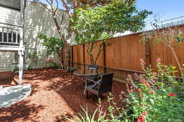 a view of a backyard with table and chairs and wooden fence
