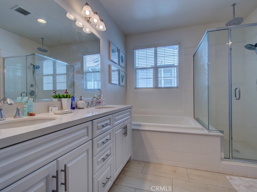 147 Acamar Irvine, CA 92618 - Photo 42 of 52 a bathroom with a double vanity sink a large mirror a bathtub and next to a window