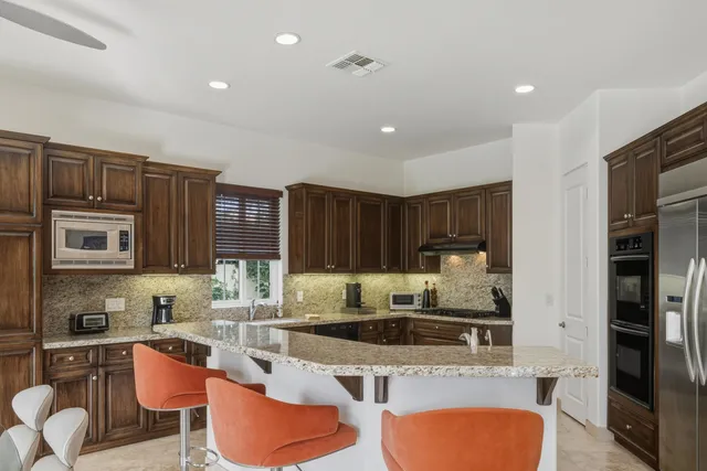 a kitchen with stainless steel appliances kitchen island granite countertop a dining table and chairs