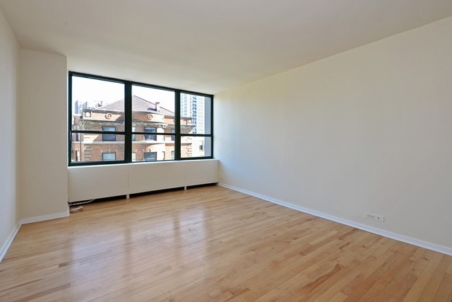 655 West Irving Park Road, Unit 312 Chicago, IL 60613 - Photo 7 of 10 an empty room with wooden floor and windows
