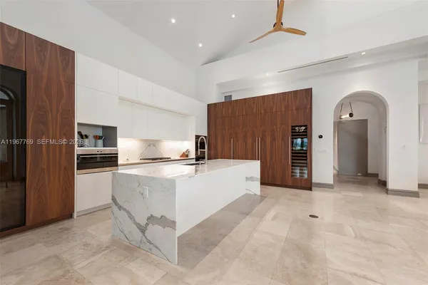 a large white kitchen with sink a refrigerator and chairs
