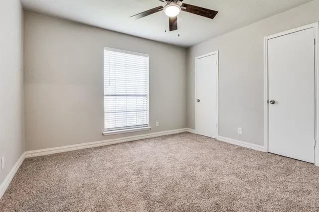 an empty room with a chandelier fan and windows