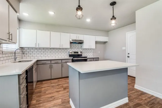 a kitchen with kitchen island a sink stainless steel appliances and cabinets
