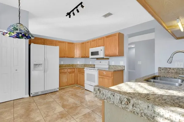 a large kitchen with a refrigerator a stove a sink a window and white cabinets