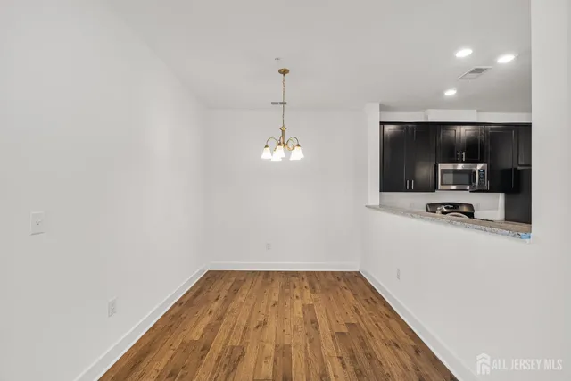 a view of a room with wooden floor a ceiling fan and windows