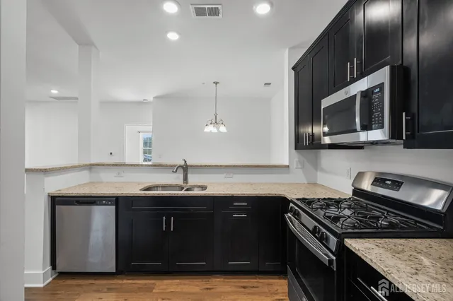 a kitchen with stainless steel appliances granite countertop a sink stove and microwave