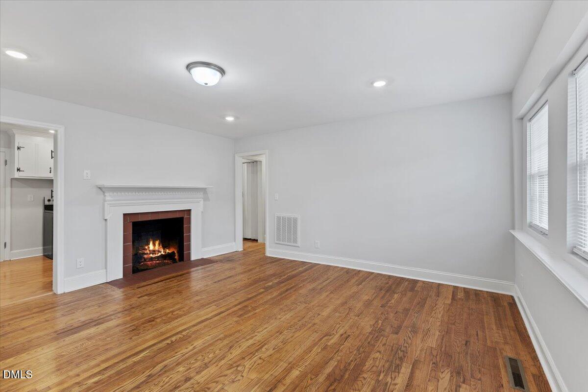 315 Hamilton Street Henderson, NC 27536 - Photo 2 of 13 a view of an empty room with wooden floor fireplace and a window