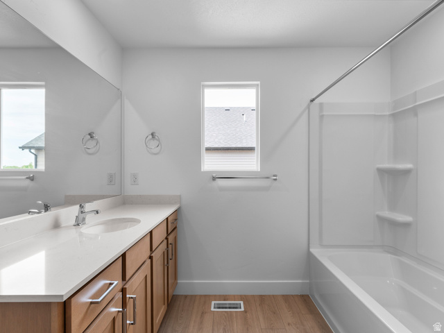 738 West 2840 South, Unit 6 Nibley, UT 84321 - Photo 18 of 23 Bathroom featuring a double vanity with stone countertops, wood-finish cabinetry, and an integrated tub and shower unit