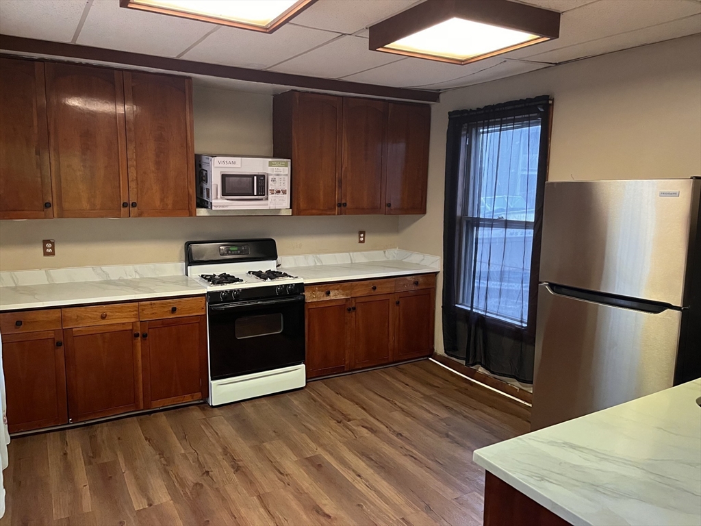6 Minot Street, Unit 6 Lynn, MA 01905 - Photo 5 of 10 a kitchen with stainless steel appliances granite countertop a refrigerator a sink dishwasher a stove with wooden cabinets and floor