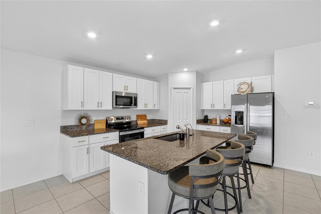 13084 Garnet Raspberry Avenue Wimauma, FL 33598 - Photo 5 of 20 a kitchen with stainless steel appliances a stove a sink a microwave a refrigerator and cabinets