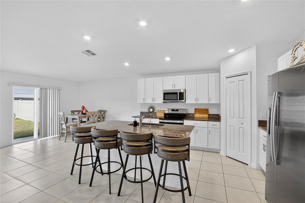 13084 Garnet Raspberry Avenue Wimauma, FL 33598 - Photo 6 of 20 a kitchen with stainless steel appliances a microwave a stove a refrigerator and a dining table