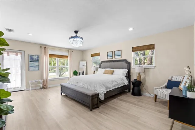 a spacious bedroom with a bed and wooden floor